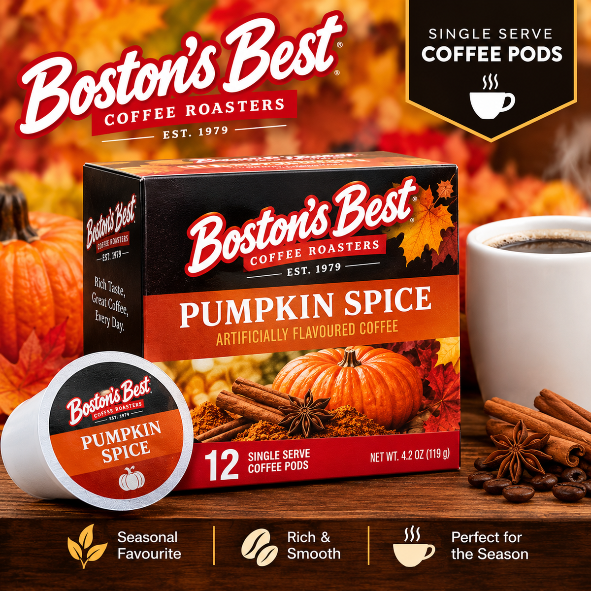 Boston's Best Coffee Roasters Pumpkin Spice single-serve coffee pods box, shown with a single pod, a white mug of coffee, pumpkins, cinnamon sticks, star anise, and autumn leaves on a wooden surface.